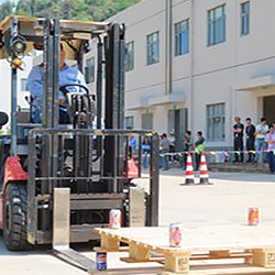 A forklift operating in an industrial yard with workers and safety barriers nearby. (photo)