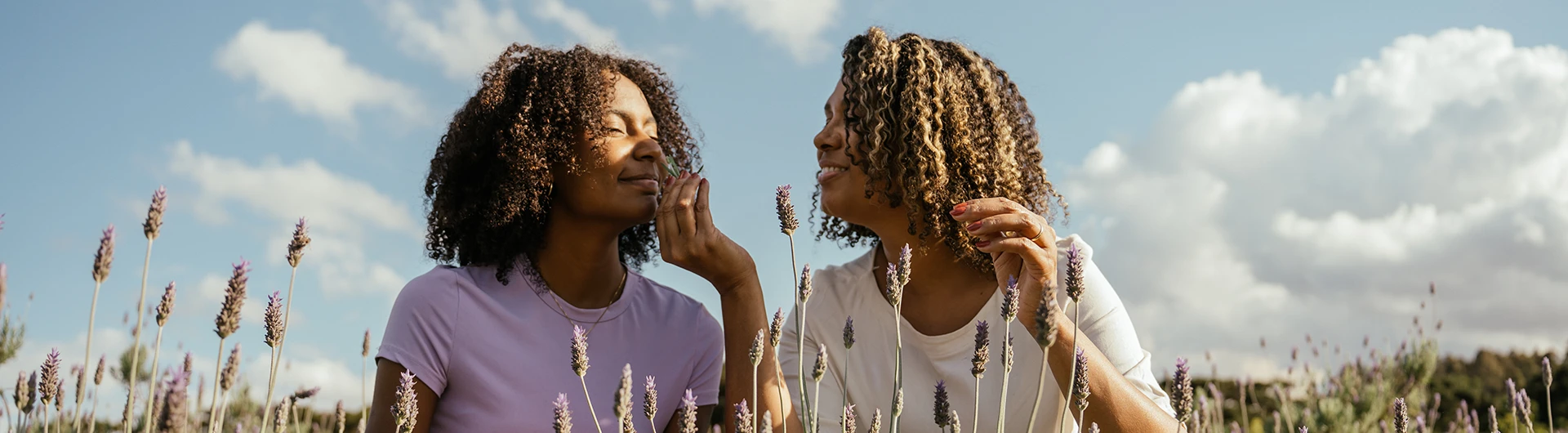 Two people standing outdoors in a field of flowers, talking and smiling. (photo)
