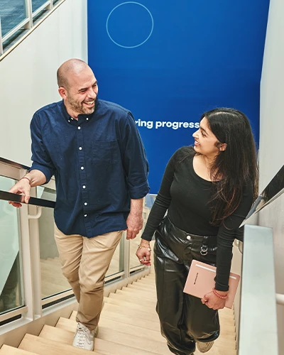 Two colleagues walking upstairs and talking at work. (photo)