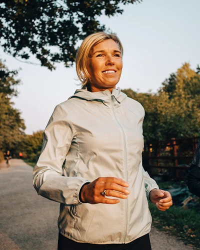 Woman jogging outdoors on a tree-lined path. (photo)